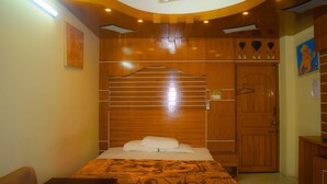 A bedroom with a bed, a wooden wardrobe, and a ceiling fan. - Hotel Diamond Palace (Cox's Bazar)