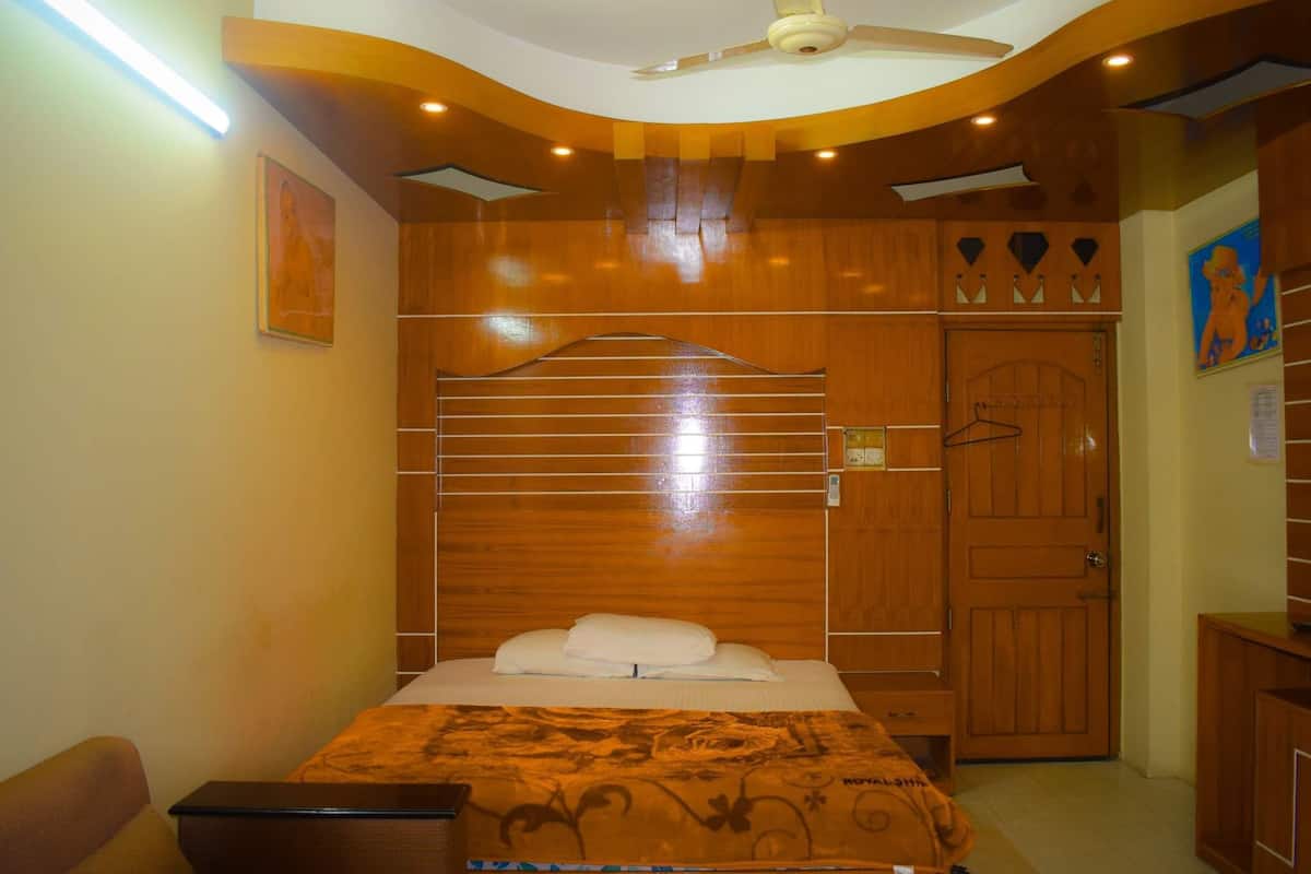 Une chambre à coucher avec un lit, une armoire en bois et un ventilateur de plafond.