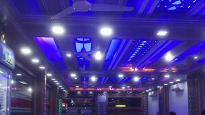 A restaurant interior with wooden tables and chairs, blue lighting, and a ceiling fan. - Hotel Diamond Palace (Cox's Bazar)