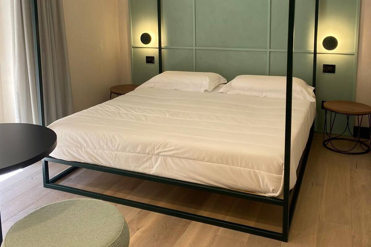 A modern bedroom with a four-poster bed, a round table, and a round ottoman.