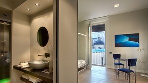 A modern bathroom with a large oval mirror, a vessel sink, and a glass shower enclosure.