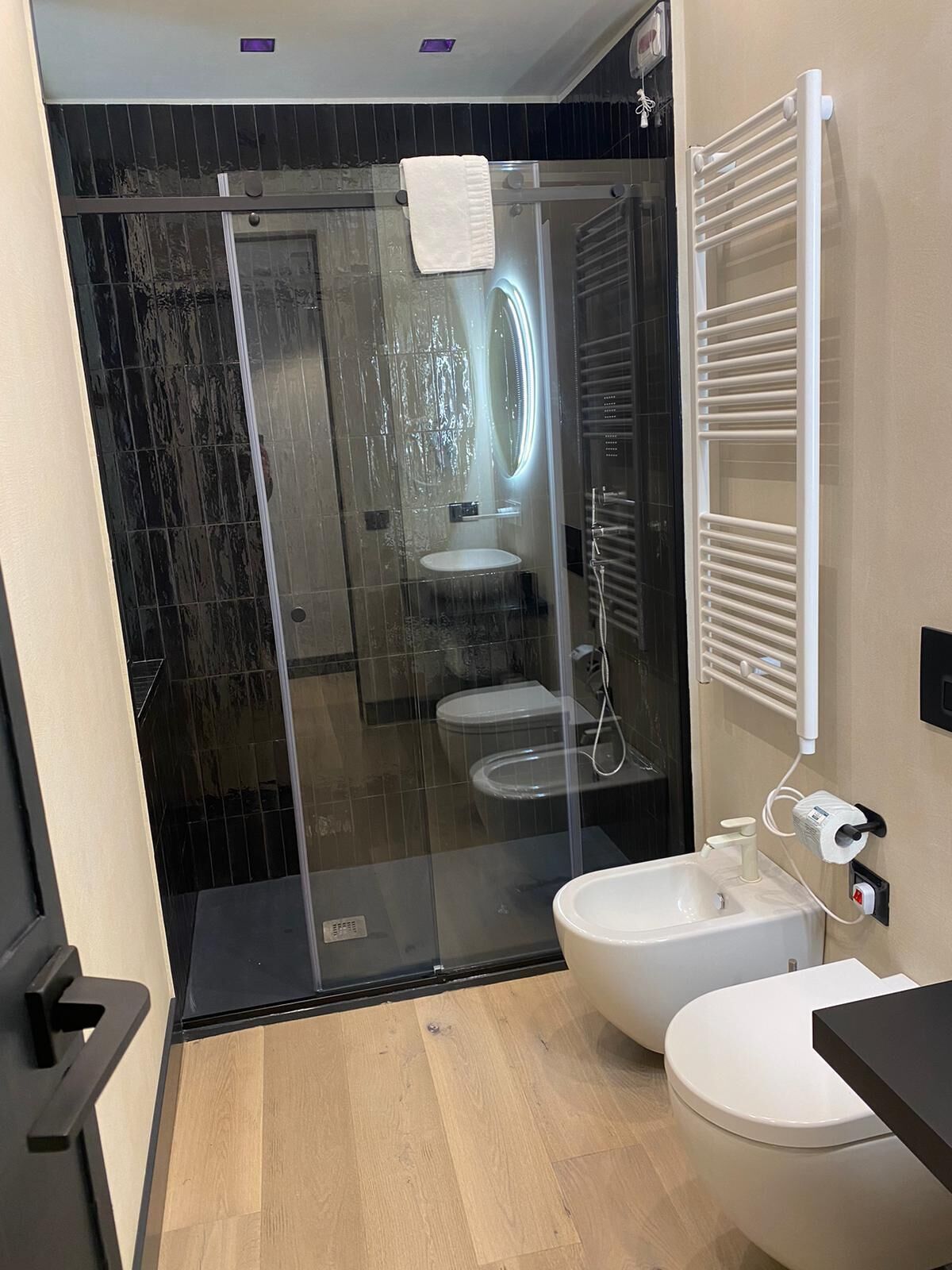 Un baño moderno con cabina de ducha de vidrio, un lavabo blanco y un inodoro.