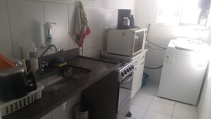 Una cocina equipada con un fregadero, estufa, microondas y refrigerador.