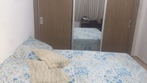 Un dormitorio con cama, dos almohadas, armario y espejo.