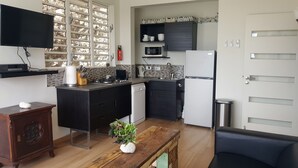 A modern kitchen with a black countertop, white appliances, and a wooden dining table with a potted plant. - LUXURY HILLTOP VILLA "Het Catshuis" - Private Pool & Panoramic Views (Willemstad)