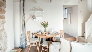 A cozy dining area with a round wooden table, chairs, and a mirror above. - 17 Farmers Meadow (Penzance)