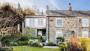 A stone house with a traditional design, featuring a front garden with various plants and a small pond. - 17 Farmers Meadow (Penzance)