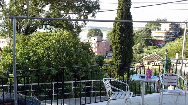 Eine Terrasse mit Metallgeländern, zwei weiße Metallstühle, ein kleiner runder Tisch und ein Blumentopf.