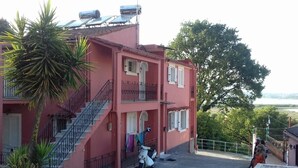 Ein pinkfarbenes Gebäude mit einer Treppe, einem Rollroller und einer Person, die auf den Stufen sitzt.