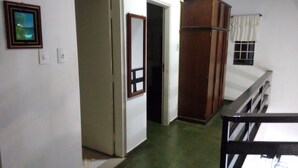 A hallway with a wooden door, a small window with curtains, and a picture on the wall. - Maresias. Spacious and comfortable house. With 4 bedrooms and close to everything. (Sâo Sebastião)