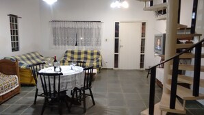 A cozy living room with a dining table, chairs, a sofa, and a television. - Maresias. Spacious and comfortable house. With 4 bedrooms and close to everything. (Sâo Sebastião)