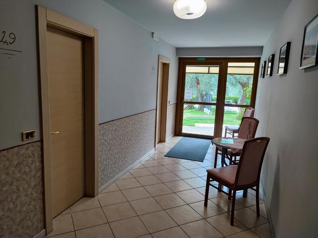 Un pasillo con una puerta marcada '29', un comedor con mesa y sillas, y vista al exterior por un ventanal.