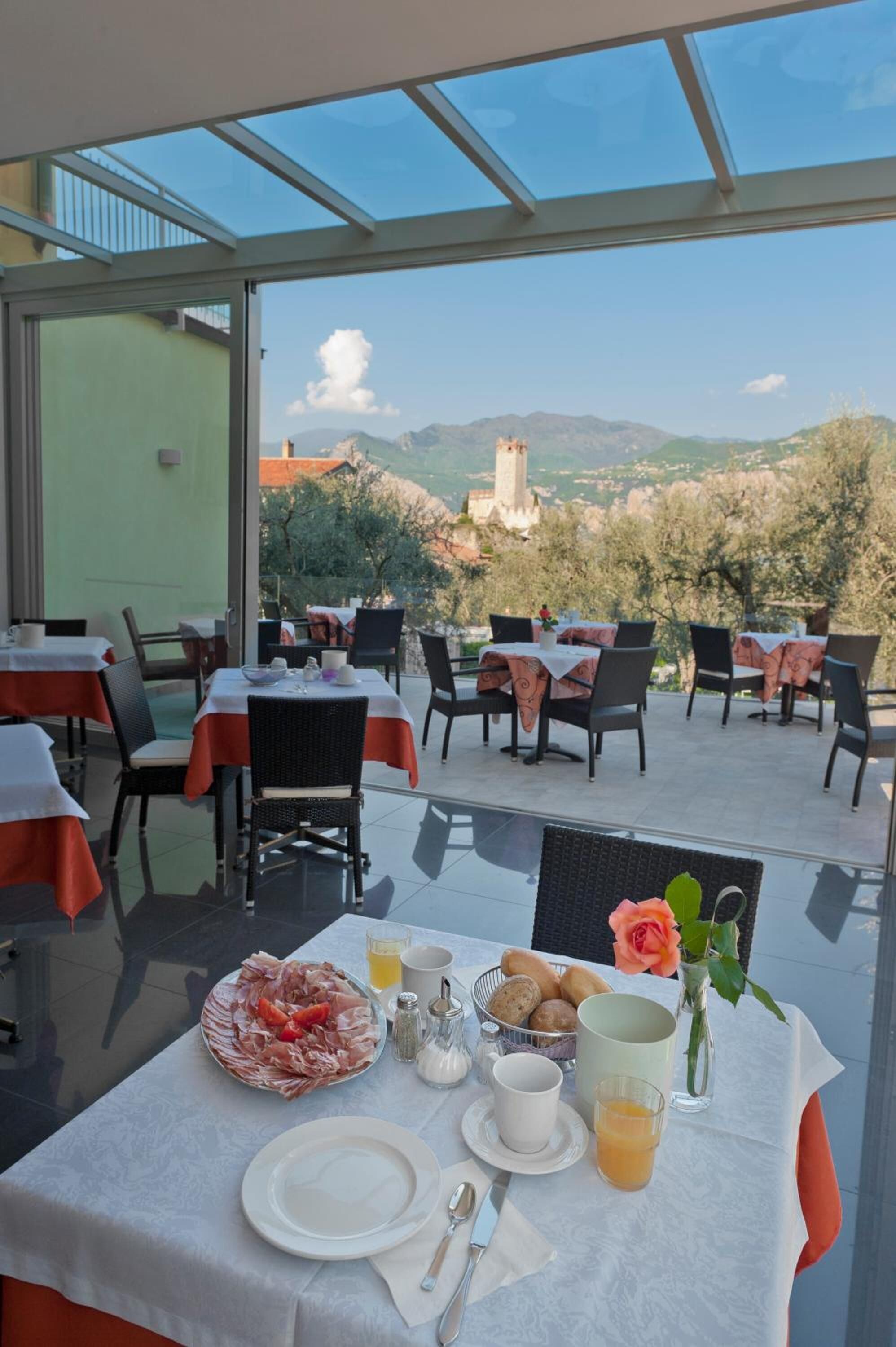 A dining area with tables set for breakfast, featuring a scenic mountain view.