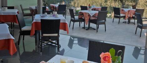 A dining area with tables set for breakfast, featuring a scenic mountain view.
