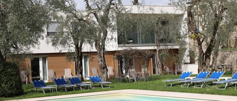 A pool area with blue lounge chairs and a modern building with balconies.