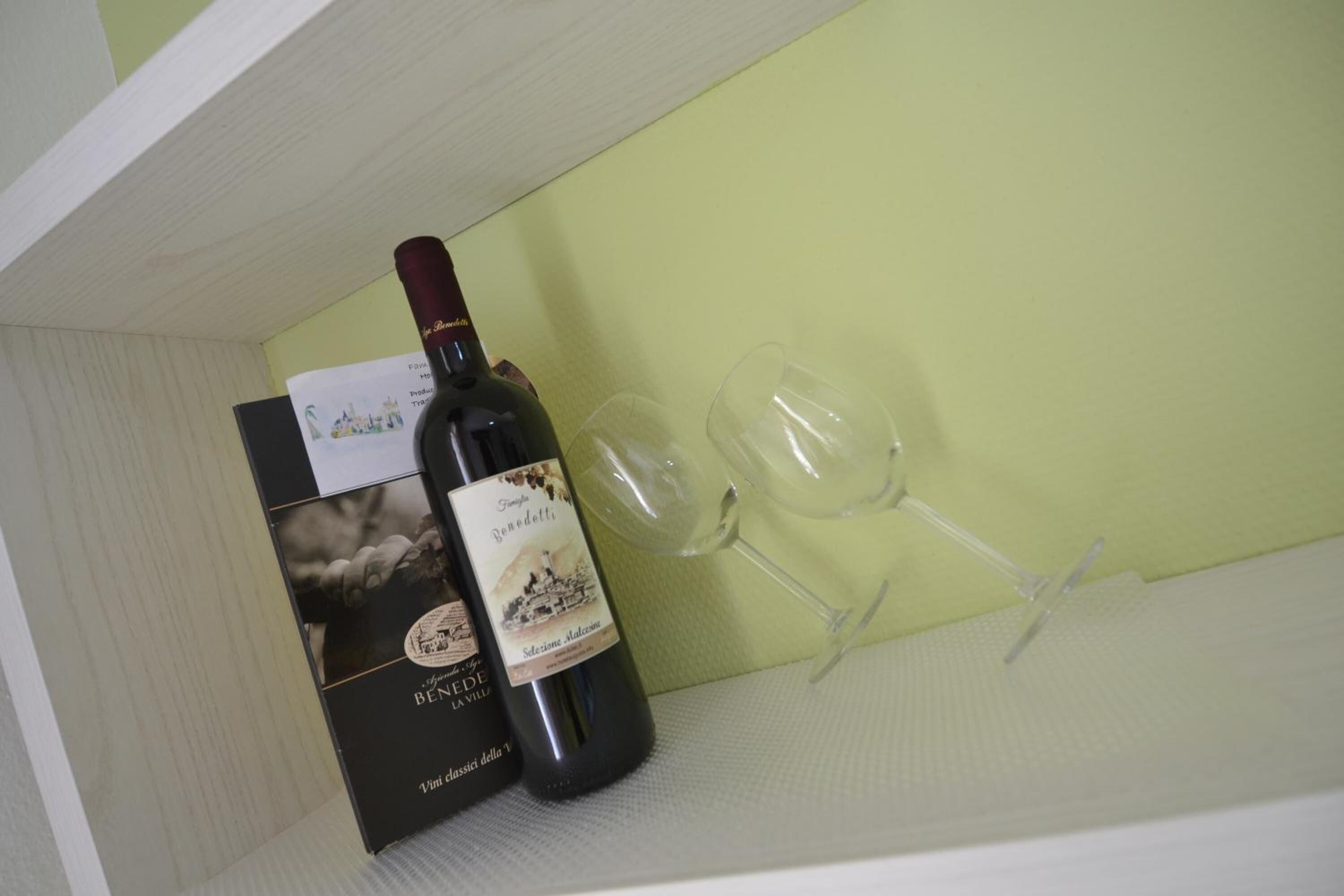 A wine bottle and two glasses on a shelf.