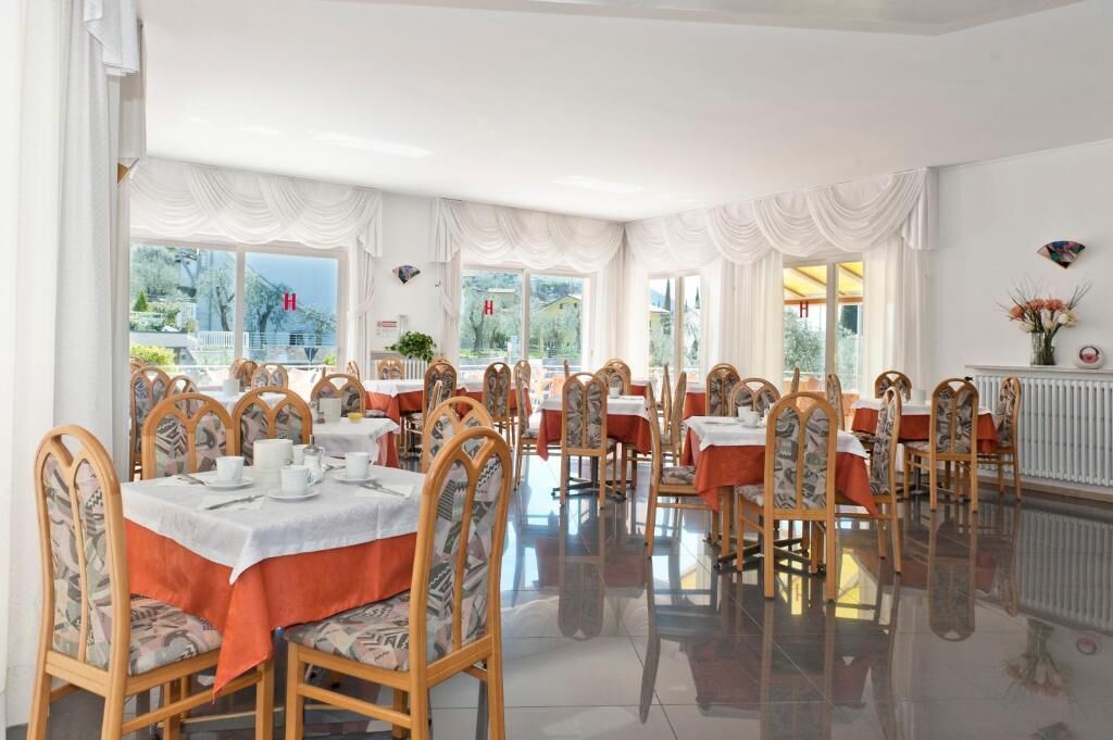 A dining area with tables set for service, chairs with patterned upholstery, and large windows offering a view of the outside.