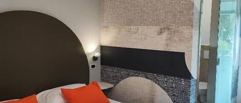 A hotel room with a large bed, a headboard, a wall with a textured pattern, and an air conditioning unit.