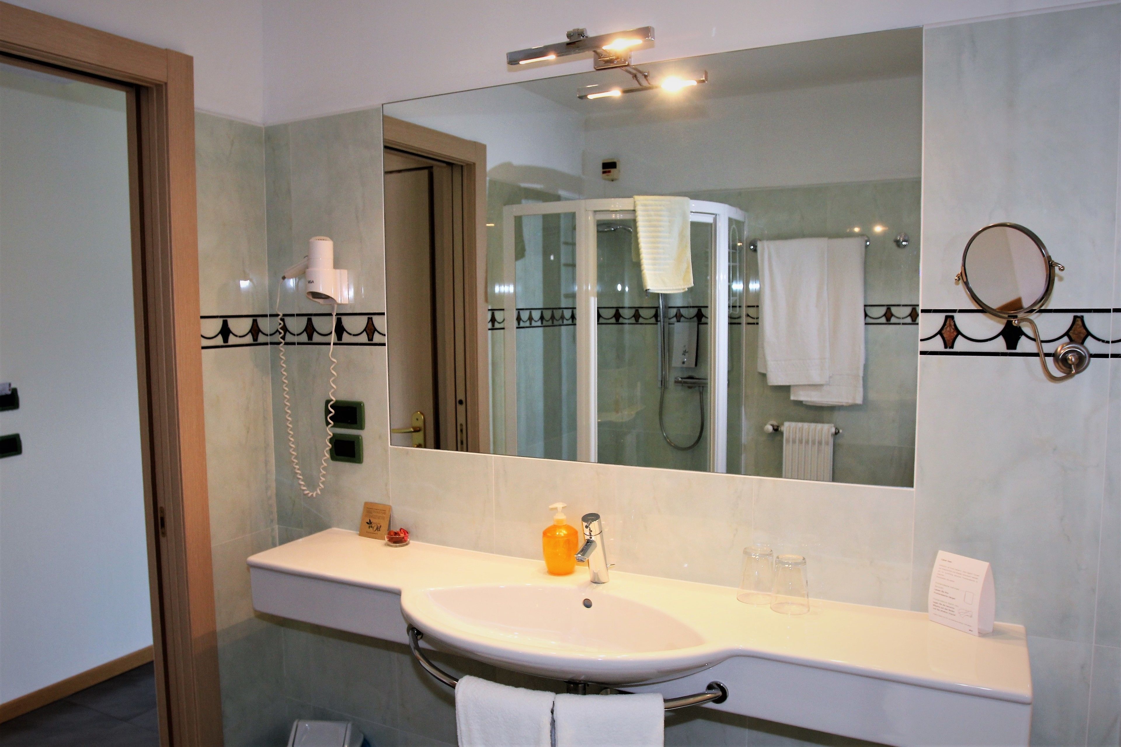 A bathroom with a sink, mirror, and a glass-enclosed shower.