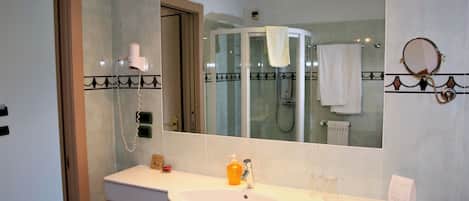 A bathroom with a sink, mirror, and a glass-enclosed shower.