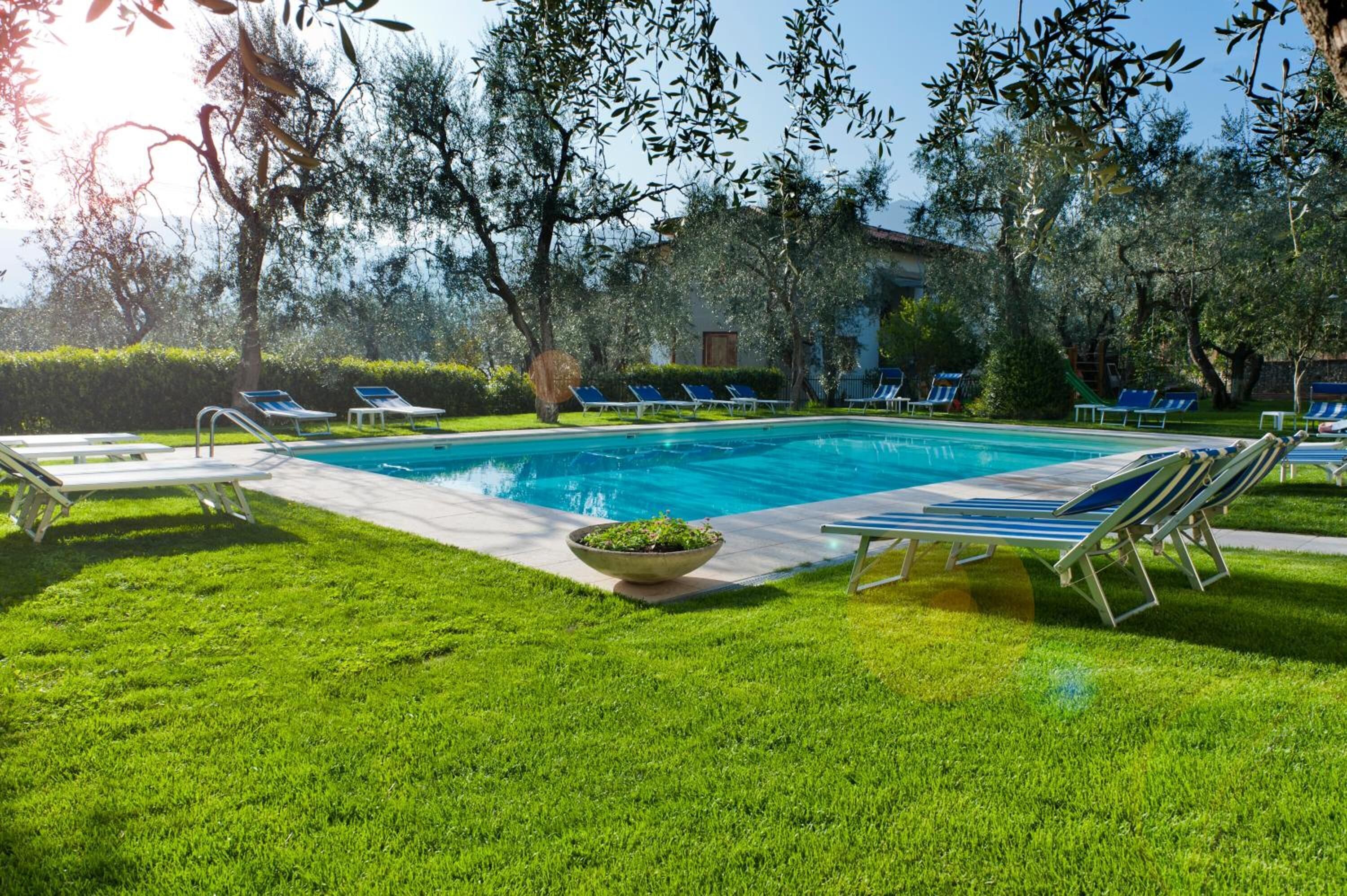 A swimming pool with lounge chairs and a grassy area.