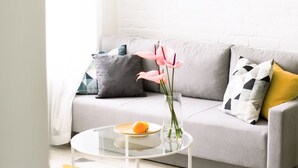 Ein modernes Wohnzimmer mit einem grauen Sofa, einem runden Couchtisch und einer schwarzen Stehlampe.