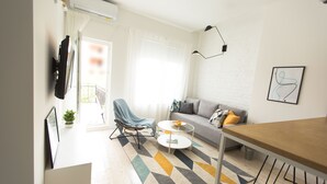 Ein modernes Wohnzimmer mit einer Couch, einem Couchtisch, einem Sessel und einem Esstisch.