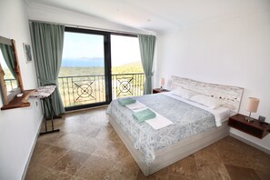 Een slaapkamer met een groot bed, een balkon en uitzicht op het landschap.