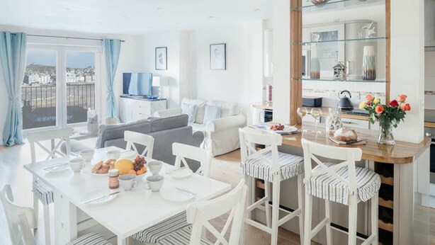 A bright living room with a dining area, a sofa, and a TV. - 10 Fernlea Court (St Ives)
