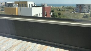 A balcony with a view of buildings and a distant body of water. - Beautiful SeaSide Apartments (Mamaia-Sat)