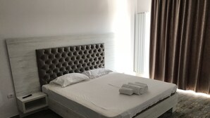 A bed with a tufted headboard, white linens, and rolled towels. - Beautiful SeaSide Apartments (Mamaia-Sat)