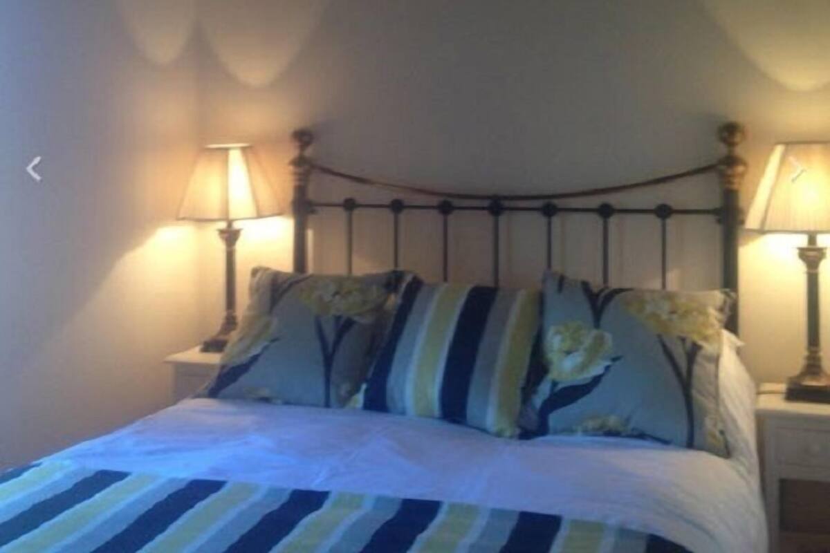 A bed with striped bedding, two bedside lamps, and floral pillows.