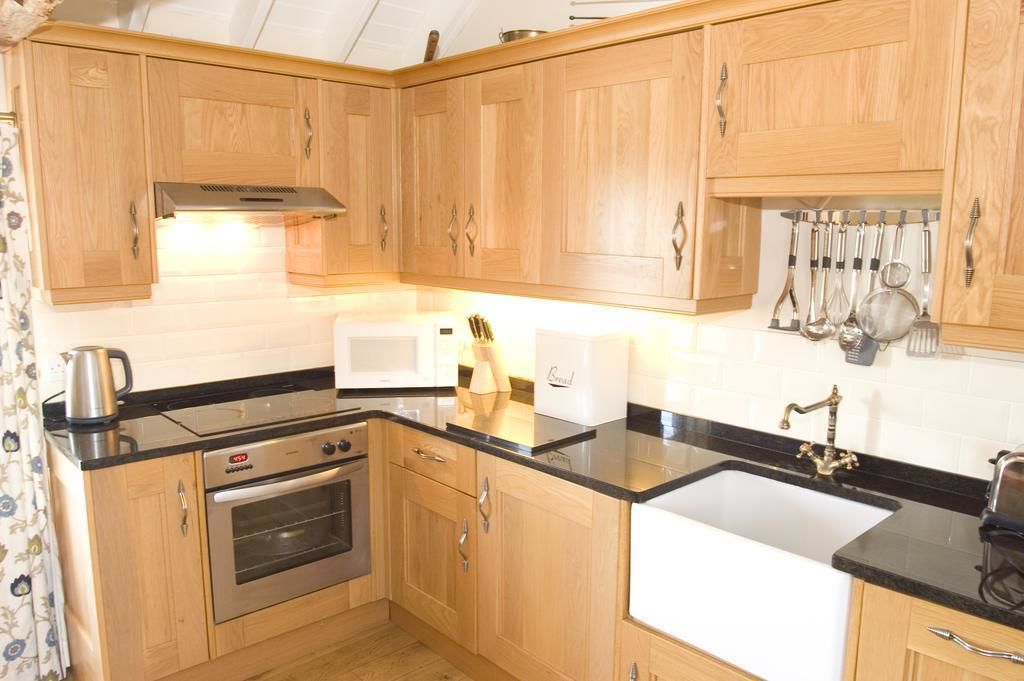 A compact kitchen with wooden cabinets, a stove, a microwave, and a sink.
