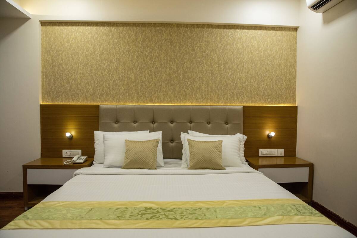 A neatly made bed with a headboard, two bedside tables with lamps, and a telephone on one of the tables.