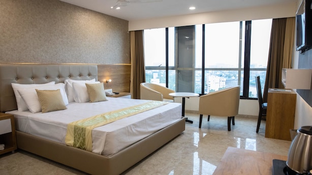 A modern hotel room with a large bed, a desk, and a view of the city. - Hotel Grace Galaxy (Mumbai)