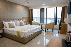 A modern hotel room with a large bed, a desk, and a view of the city. - Hotel Grace Galaxy (Mumbai)