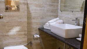 A modern bathroom with a white toilet, a large sink, and a mirror. - Hotel Grace Galaxy (Mumbai)