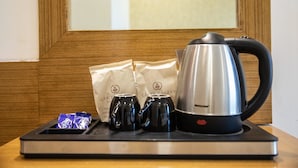 A tray with a kettle, two mugs, and two paper bags on a wooden table. - Hotel Grace Galaxy (Mumbai)