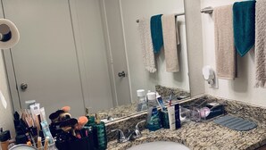 Ein Badezimmer mit einer Granitplatte, einem Waschbecken, einem Spiegel und einem Handtuchhalter mit zwei Handtüchern.