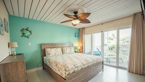 Una camera da letto con un letto, una ventola a soffitto, una finestra con tende e vista sull'esterno.