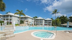 Un resort con una grande piscina, numerosi balconi e palme.