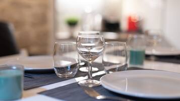 A dining table set with clear glasses, a white plate, and a blue candle.