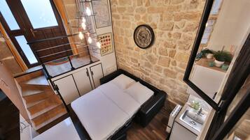 Une pièce de taille modeste comprenant un lit, un petit lavabo et un escalier menant à un niveau supérieur.