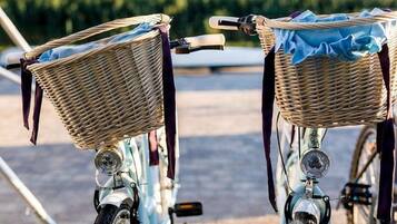 Dos bicicletas antiguas con cestas de mimbre y cubiertas de tela azul, estacionadas al aire libre.