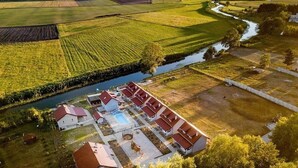 Vue aérienne d’une propriété comprenant plusieurs bâtiments, une piscine et une rivière.