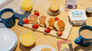 A breakfast table with scones, strawberries, a box of Roda's clotted cream, a jar of jam, a mug of coffee, a glass of orange juice, and a box of Cornwall's chocolate cove biscuits. - 8 Sunday School Court (St Ives)