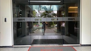 L’entrée d’un hôtel avec des portes en verre portant l’inscription « CAIAPÓ » et un tapis rouge avec l’inscription « EDIFICIO CAIAPÓ ».