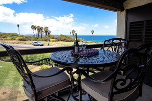 Un patio con una mesa redonda y sillas, una botella de champán y copas sobre la mesa.