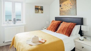 Una habitación de hotel con una cama, un ventanal con vistas y un cuadro en la pared.