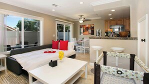 A modern living room with a sofa, a dining table, and a kitchen area visible through an open door. - Multi-Level 2BR-Fast WiFI-Free Parking!-CM1 (Costa Mesa)